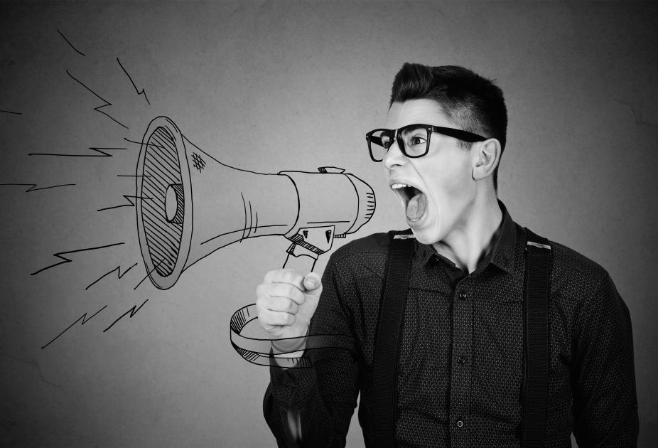 A man with glasses passionately shouting into a megaphone to advertise offering