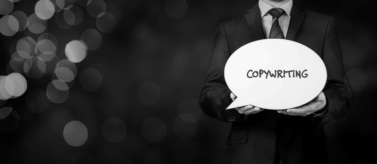 A businessman holding a speech bubble with the word copywriting.